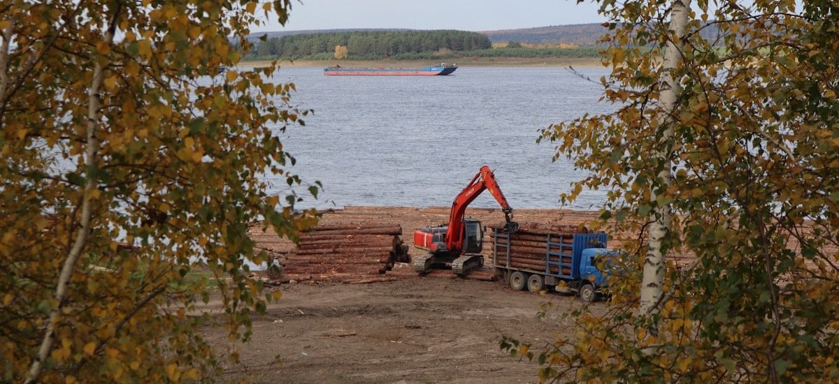 a crane is working on a pile of logs
