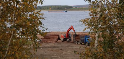 a crane is working on a pile of logs